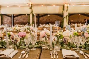 Long tables dressed for wedding breakfast with floral displays and cutlery: wedding marquee hire