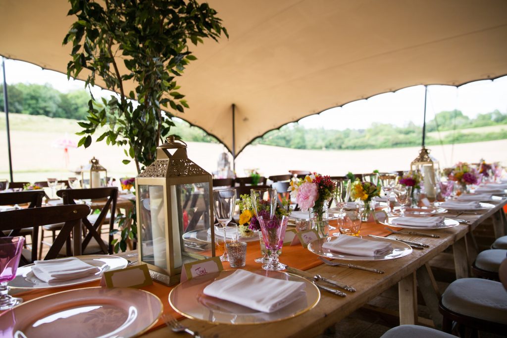 A Stretch tent with dining tables laid out for an event and views to the gardens beyond. Marquee hire FAQs