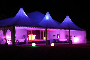 how do I hire a marquee? Three pagoda marquees side by side with purple LED lighting, at night. Marquee hire FAQs